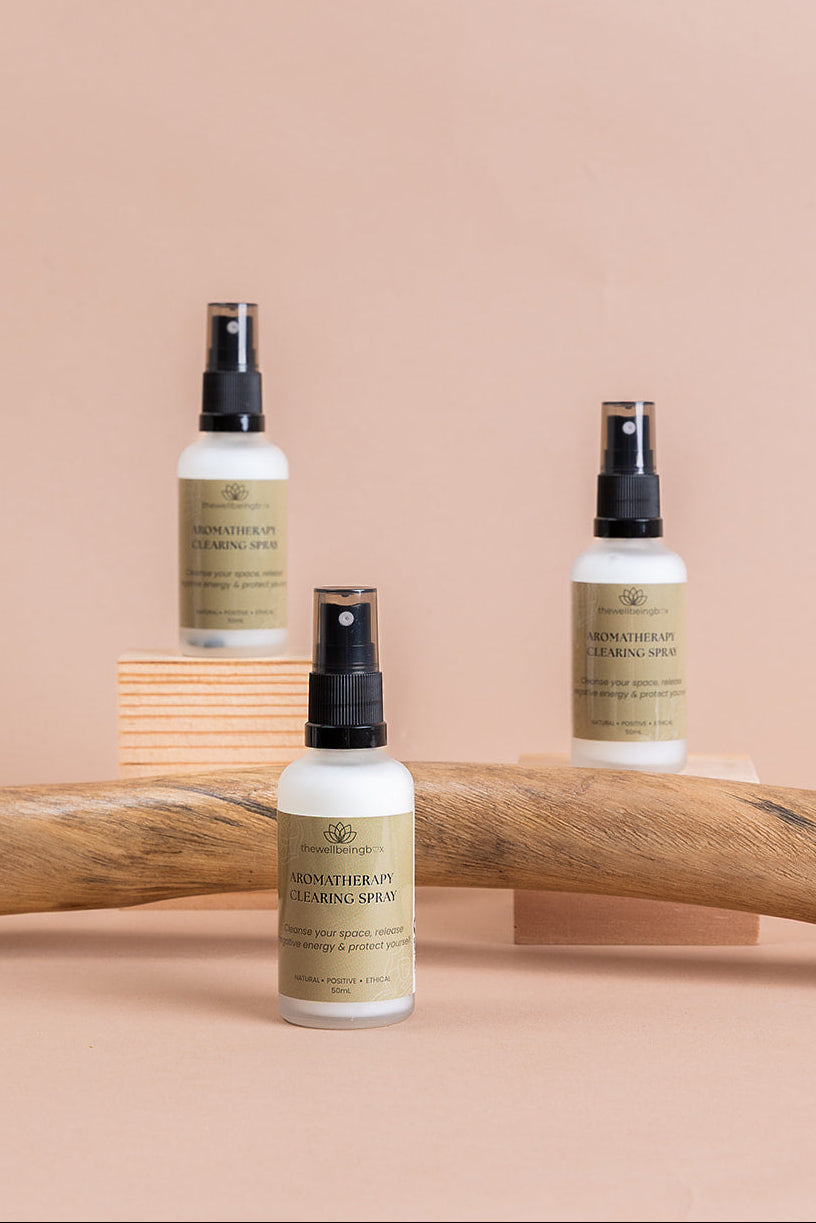 Three aromatherapy mist clearing sprays resting on driftwood.